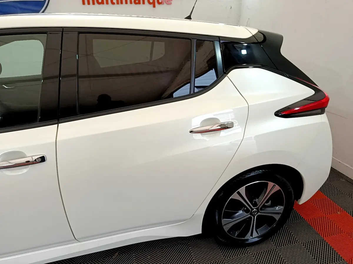 Vue côté droit arrière du Nissan Leaf blanc 62 kWh avec vitres teintées et feux arrière distinctifs en forme de boomerang.