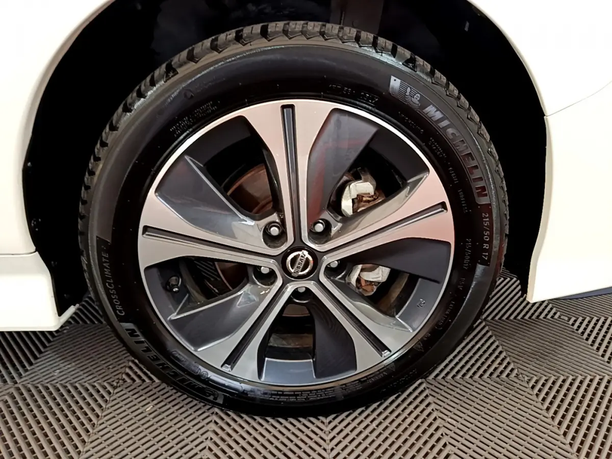 Gros plan sur la roue avant droite d'une Nissan Leaf blanche, jante alliage bicolore et pneu Michelin visible.