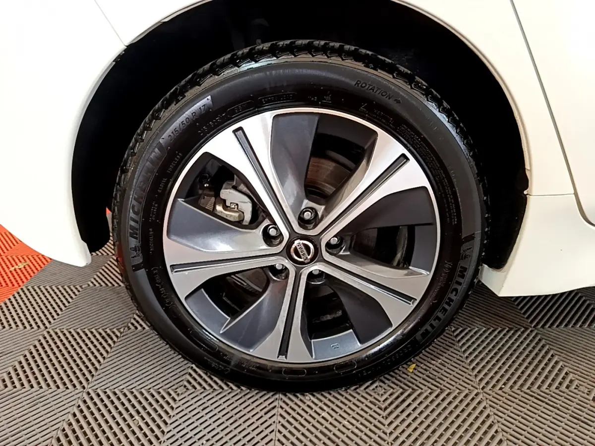 Gros plan sur la roue avant droite avec jante alliage bicolore du Nissan Leaf blanc 2020 électrique.