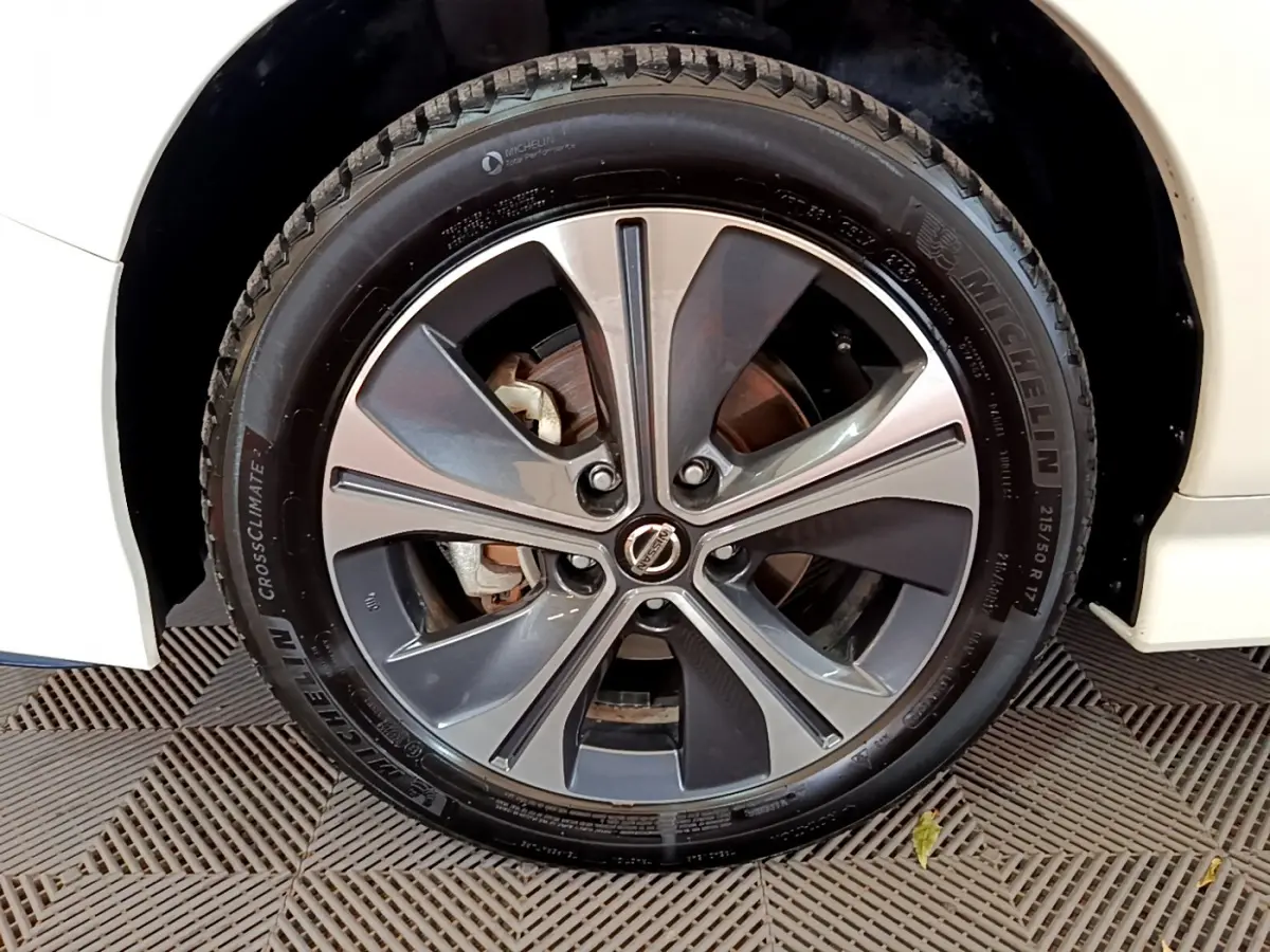 Gros plan sur la roue avant droite d'une Nissan Leaf blanche, jante alliage à cinq branches doubles et pneu Michelin.
