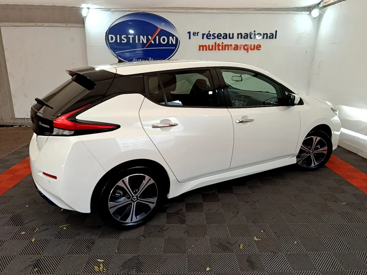 Vue côté droit d'une Nissan Leaf blanche 2020 avec toit noir, feux arrière en forme de boomerang et jantes stylisées.