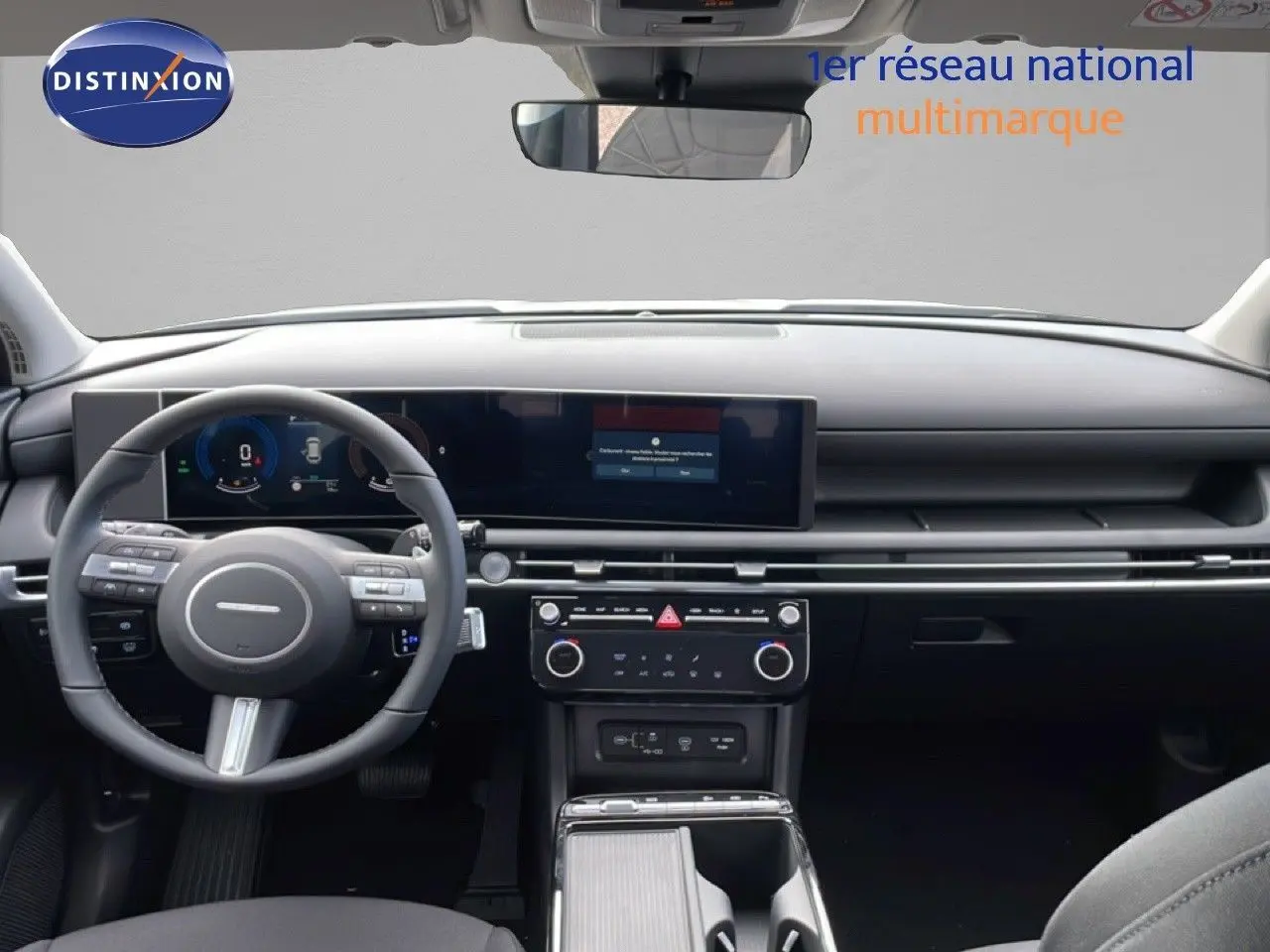 Vue intérieure avant du Hyundai Tucson 2026 avec tableau de bord noir et écran tactile panoramique.