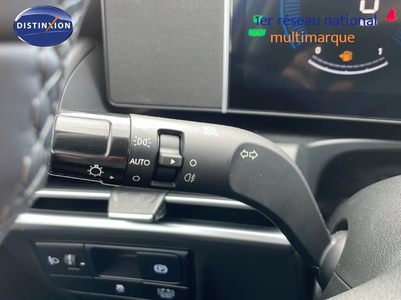 Gros plan sur la commande des feux et clignotants à gauche du volant dans l’habitacle du Hyundai Tucson blanc.