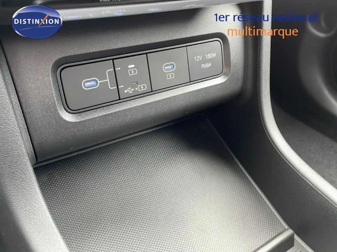 Gros plan sur la console centrale du Hyundai Tucson 2026, montrant les ports USB et prise 12V dans un intérieur noir.