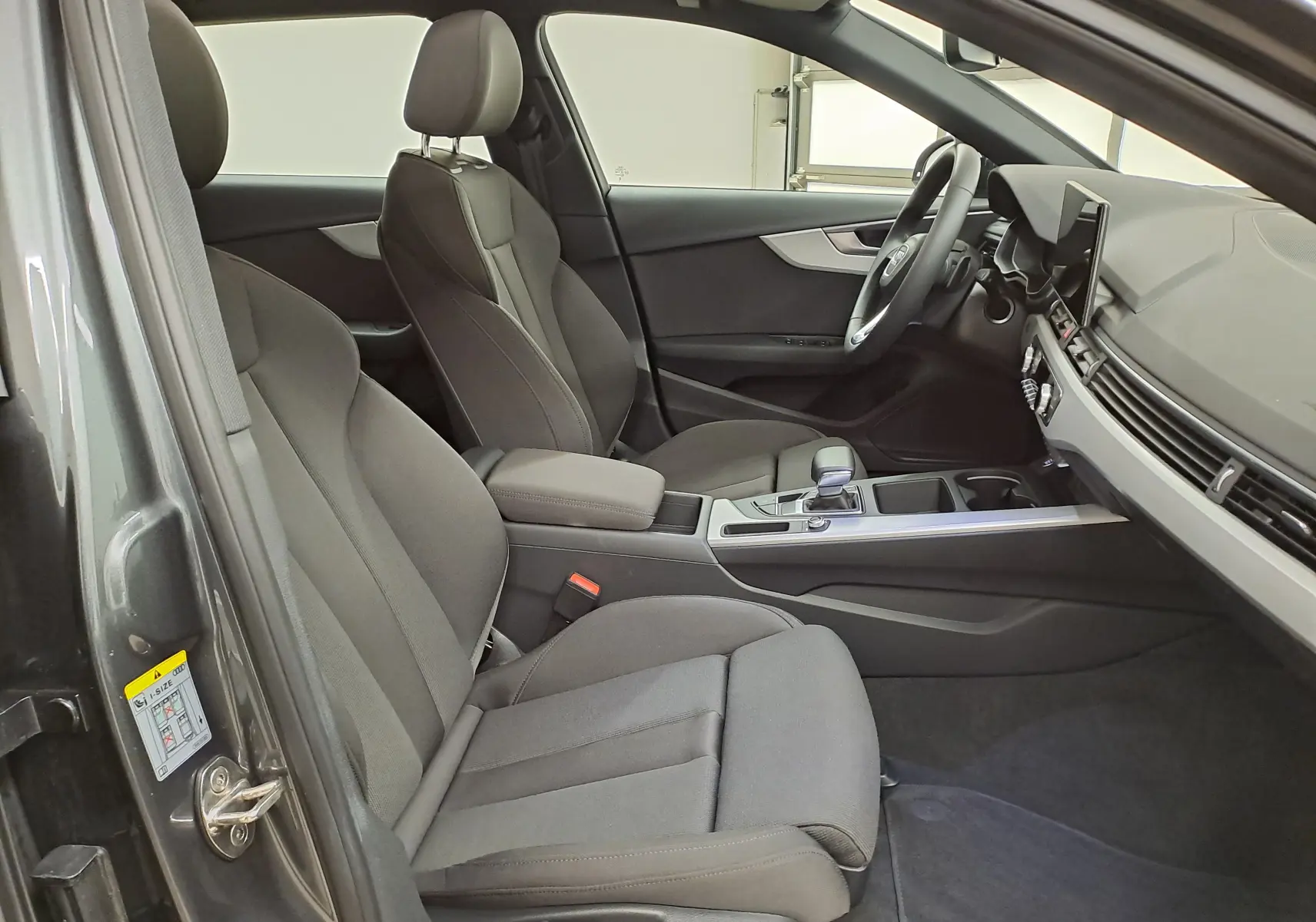 Intérieur avant droit de l'Audi A4 Avant 40 TDI gris Daytona, sièges tissu gris et tableau de bord moderne.