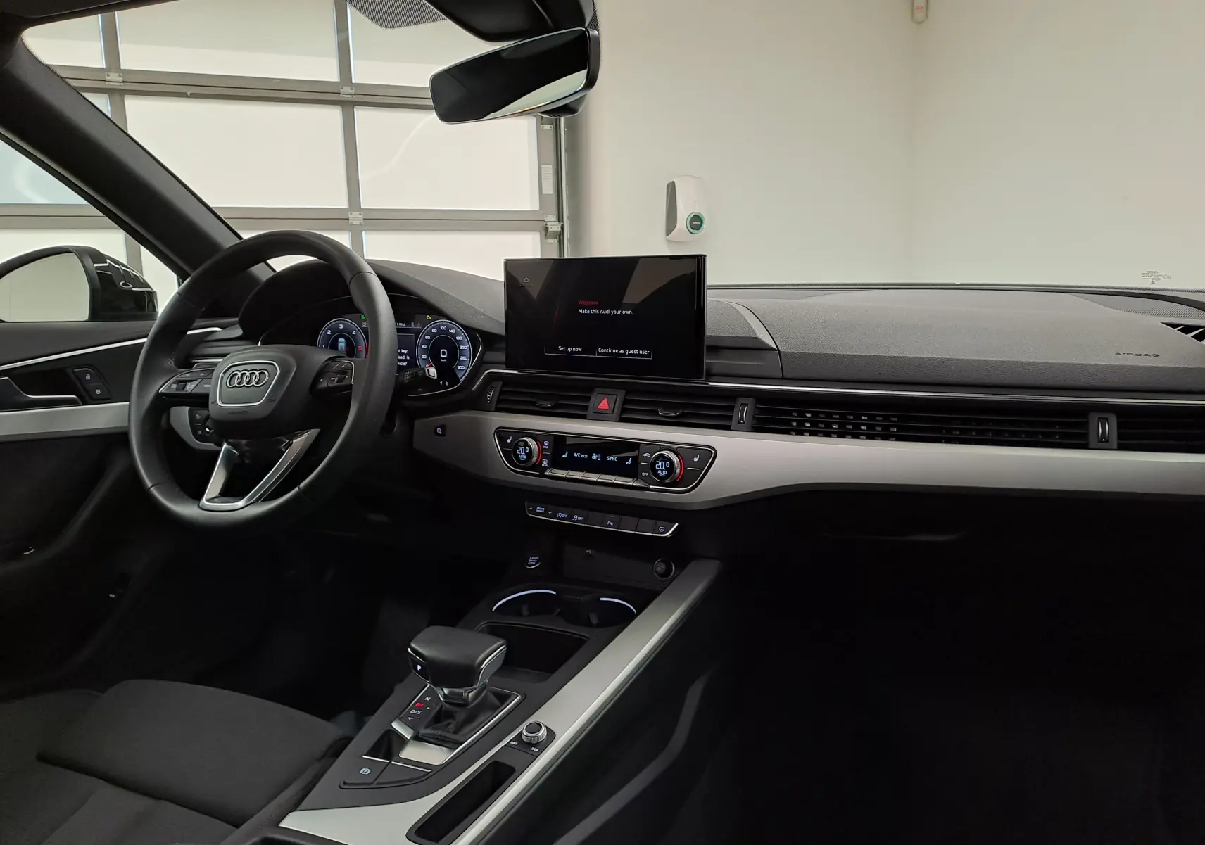 Intérieur de l'Audi A4 Avant 40 TDI 2024 vu côté conducteur, tableau de bord moderne et écran central allumé.