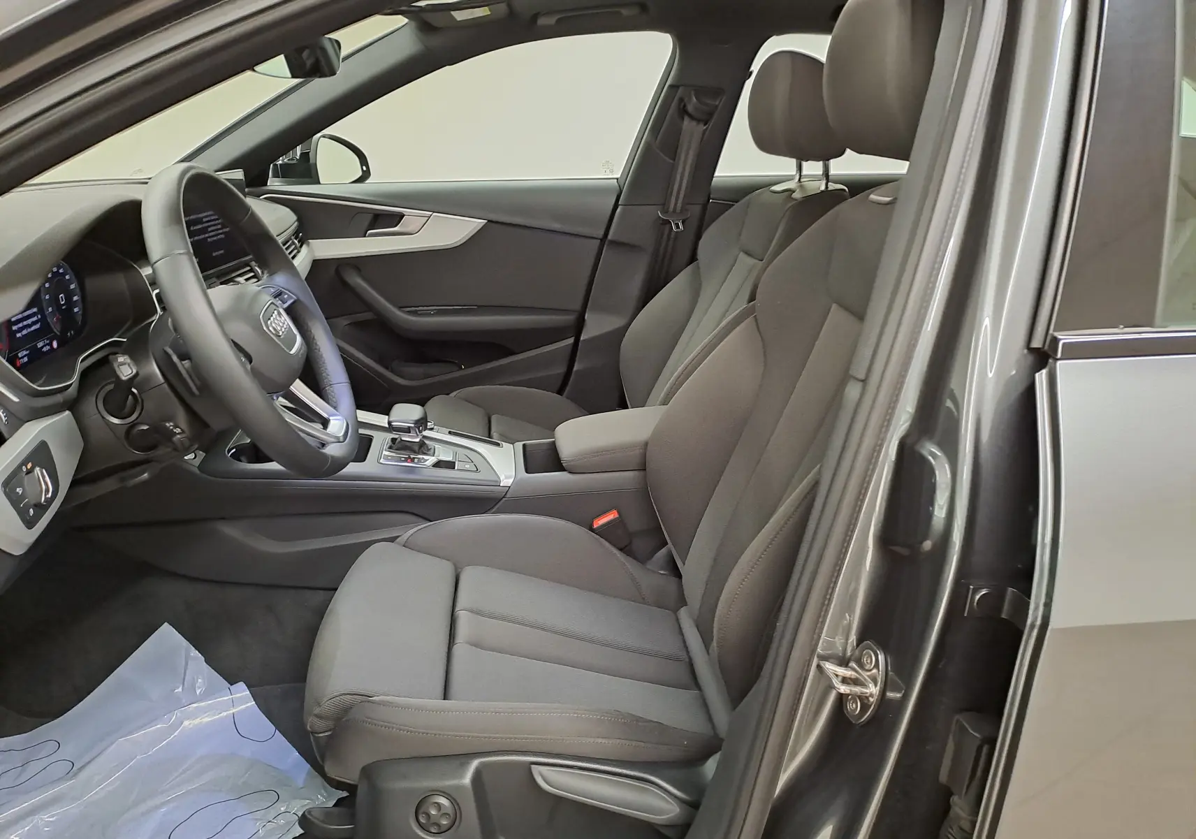 Intérieur avant droit d'une Audi A4 Avant 40 TDI 2024 gris Daytona, sièges tissu noirs et tableau de bord moderne.