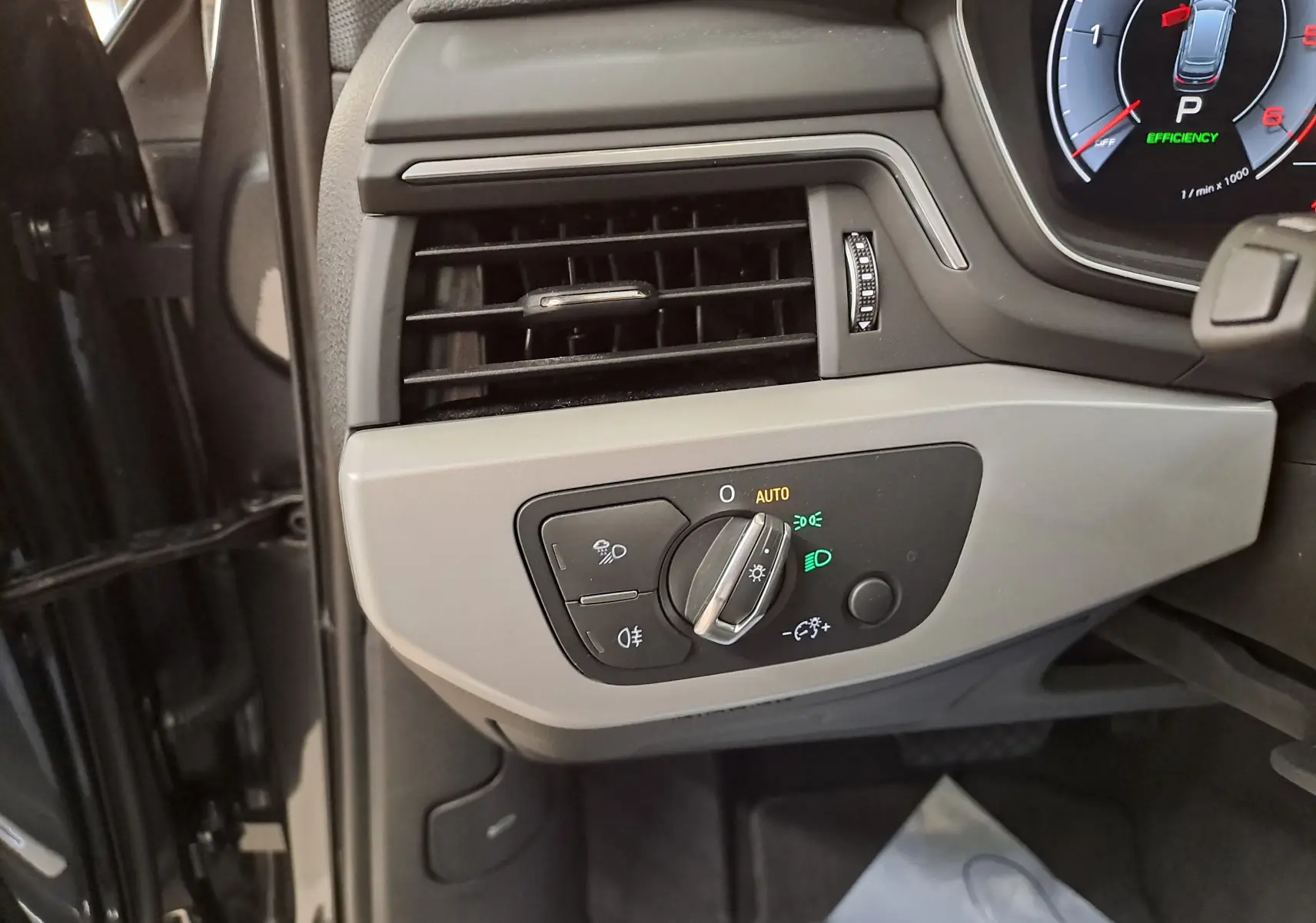 Gros plan sur la commande des feux à gauche du tableau de bord de l'Audi A4 Avant gris Daytona 2024