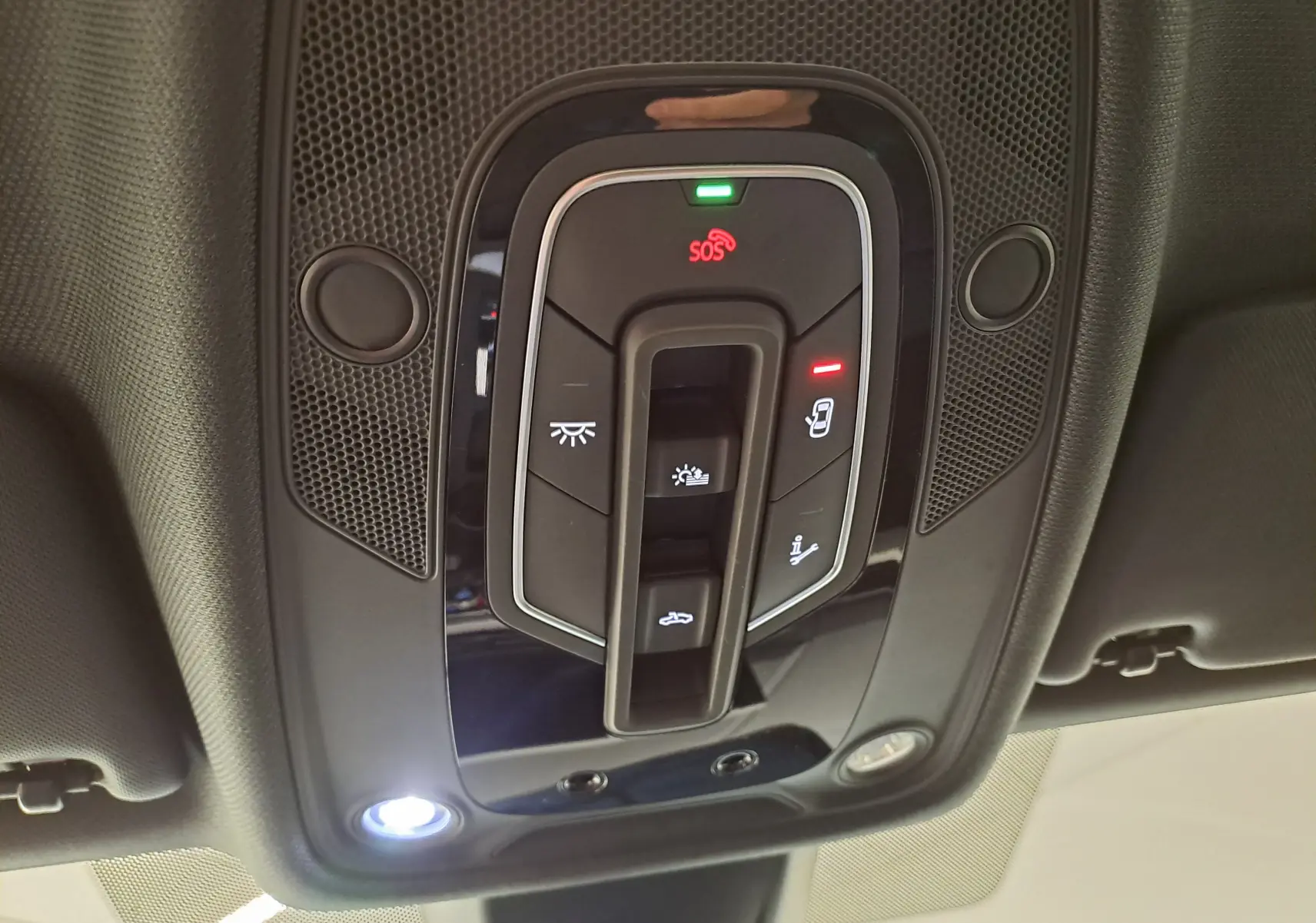 Vue en gros plan du panneau de commandes au plafond de l'Audi A4 Avant 40 TDI gris Daytona, avec éclairage et boutons SOS visibles.