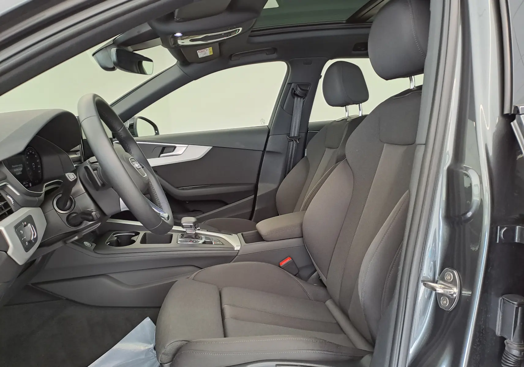 Intérieur côté conducteur de l'Audi A4 Avant 40 TDI gris Daytona, sièges tissu et toit panoramique ouvert.