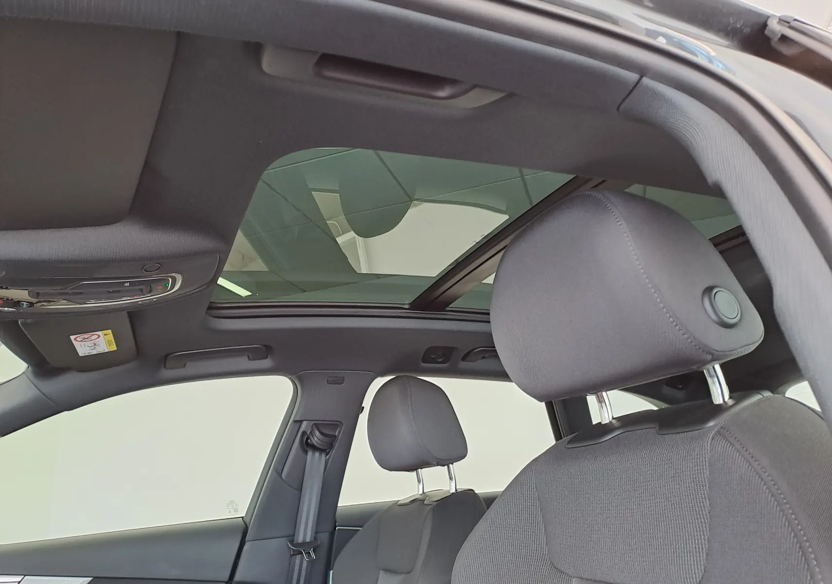 Vue intérieure du toit panoramique en verre et des sièges avant noirs de l'Audi A4 Avant Gris Daytona 2024.