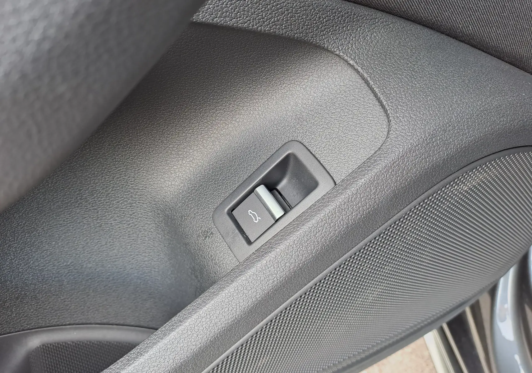 Détail du bouton d'ouverture du coffre sur la porte côté gauche d'une Audi A4 Avant Gris Daytona 2024.
