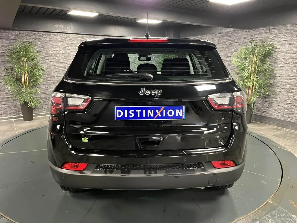 Vue arrière d'un Jeep Compass noir 2024 avec logo Jeep et feux arrière LED dans un showroom.