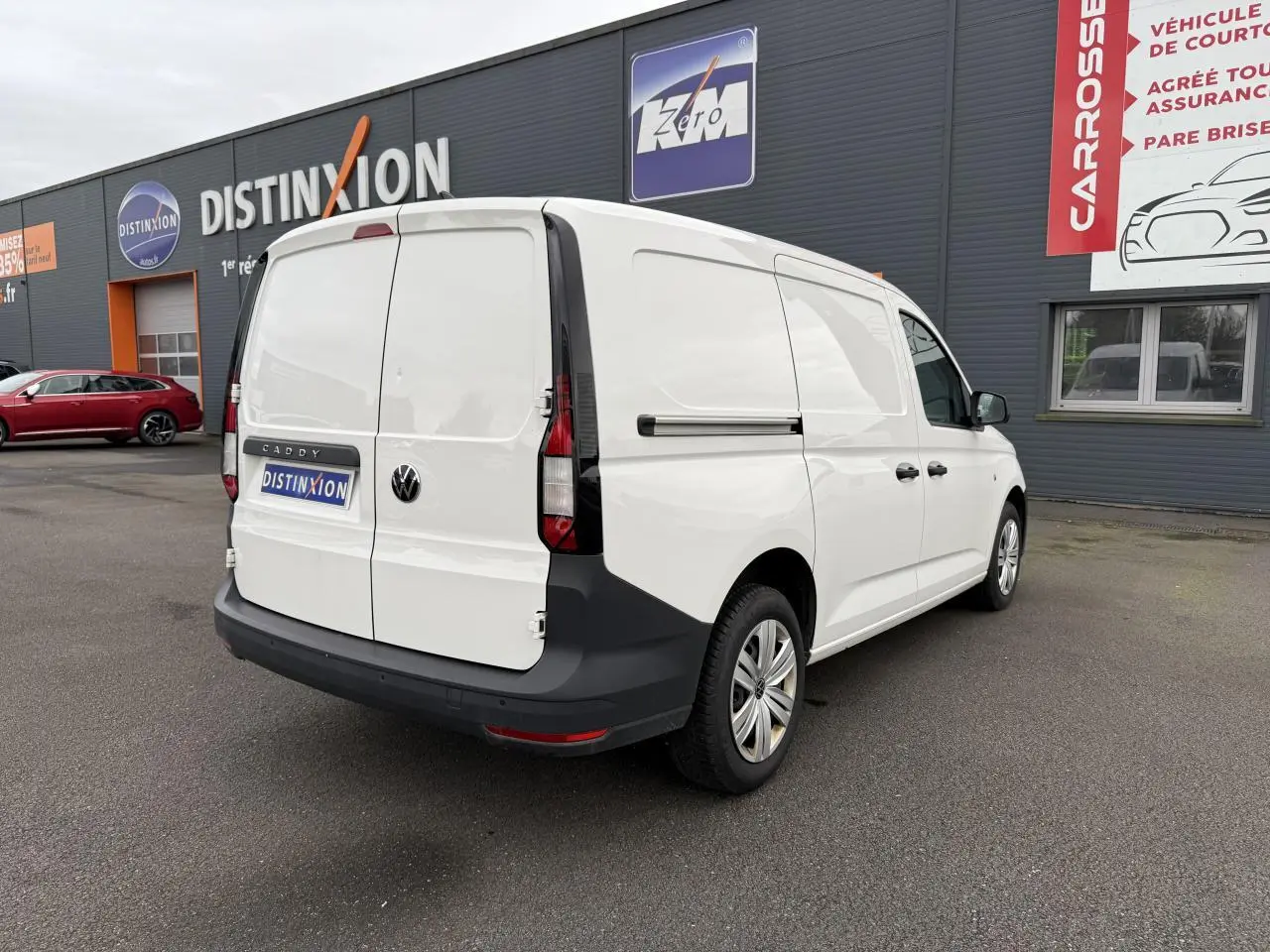 Vue 3/4 arrière droite d'un Volkswagen Caddy Maxi Cargo blanc Candy avec portes arrière battantes et pare-chocs noir.