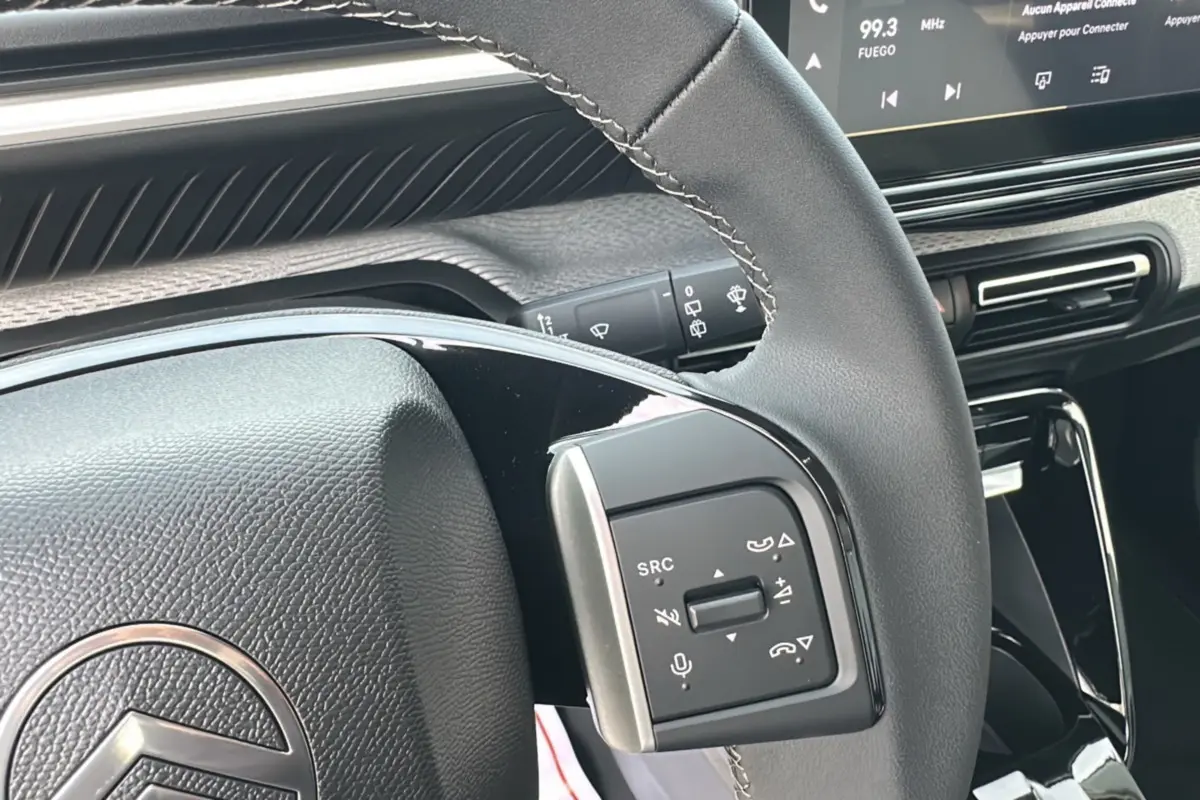 Gros plan sur le volant cuir multifonctions de la Citroën C3 Aircross Hybrid 145 avec tableau de bord tactile en arrière-plan.
