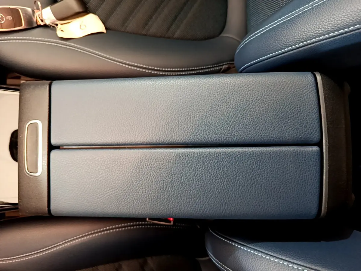 Vue rapprochée du couvercle de la console centrale en cuir noir entre les sièges avant d'une Mercedes Classe A 180 d 2020.