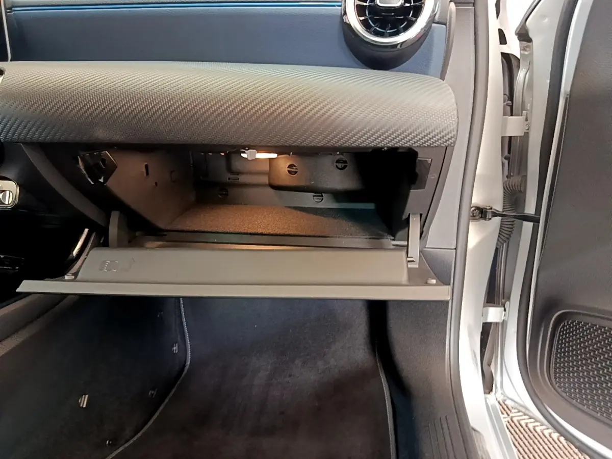 Vue intérieure côté passager de la boîte à gants ouverte du Mercedes Classe A gris clair 2020, avec éclairage intérieur.