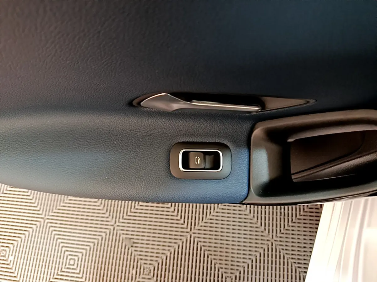 Bouton de verrouillage des portes sur la garniture intérieure noire de la porte côté droit d'une Mercedes Classe A gris clair.