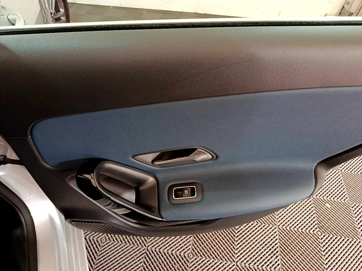 Gros plan sur la porte côté gauche gris clair de la Mercedes Classe A 180 d Business Line avec insert bleu et poignée noire.