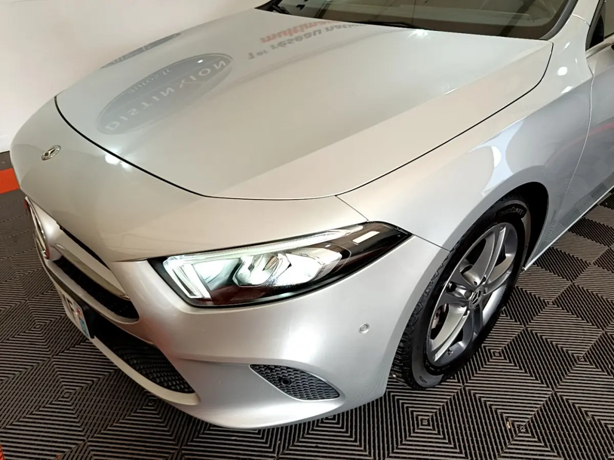 Vue 3/4 avant droit d'une Mercedes Classe A A 180 d Business Line gris clair avec phares LED allumés et jantes alliage.
