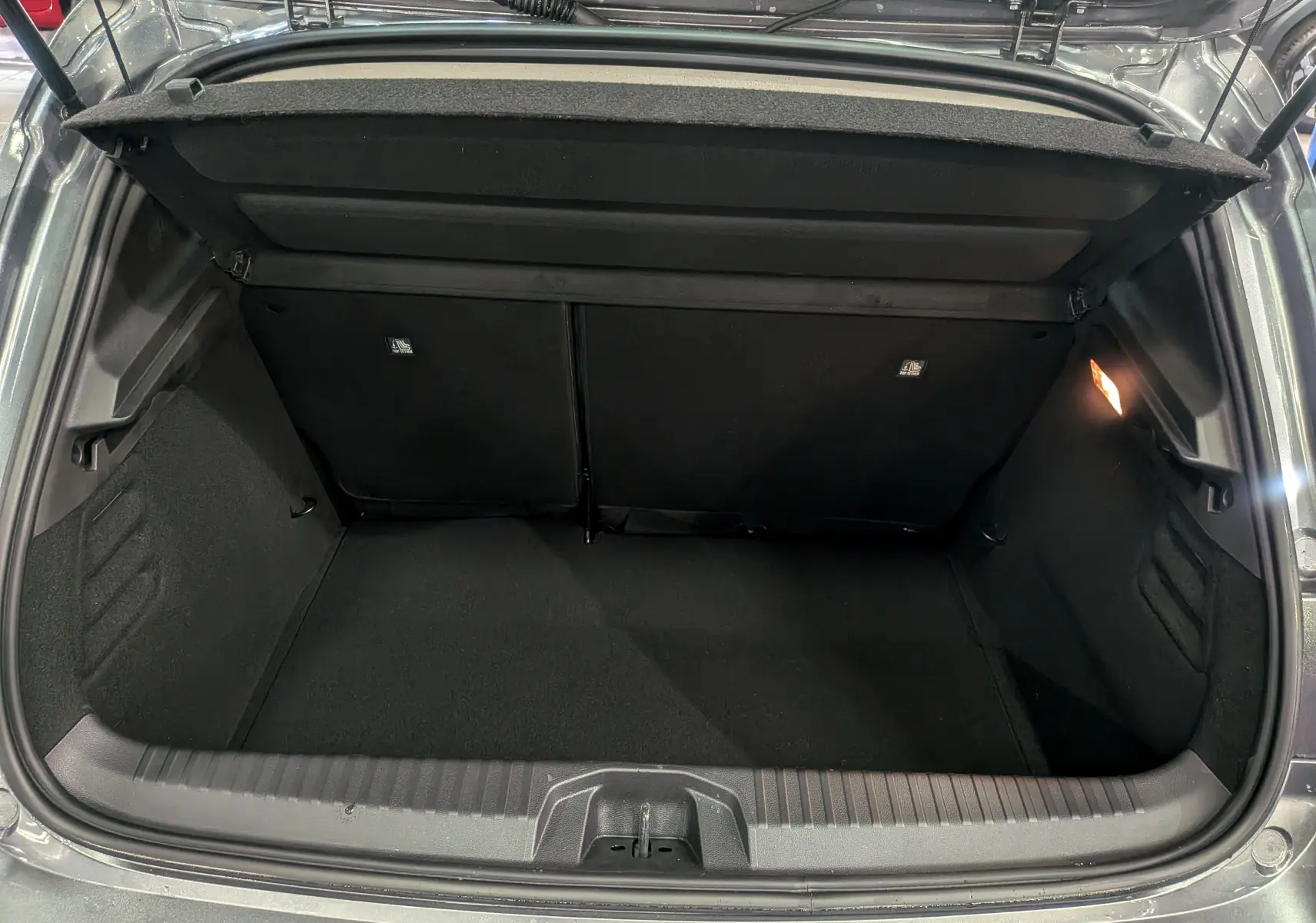 Coffre ouvert vu de l'arrière d'une Renault Clio V Gris Schiste 2025, montrant un espace de chargement propre et éclairé.