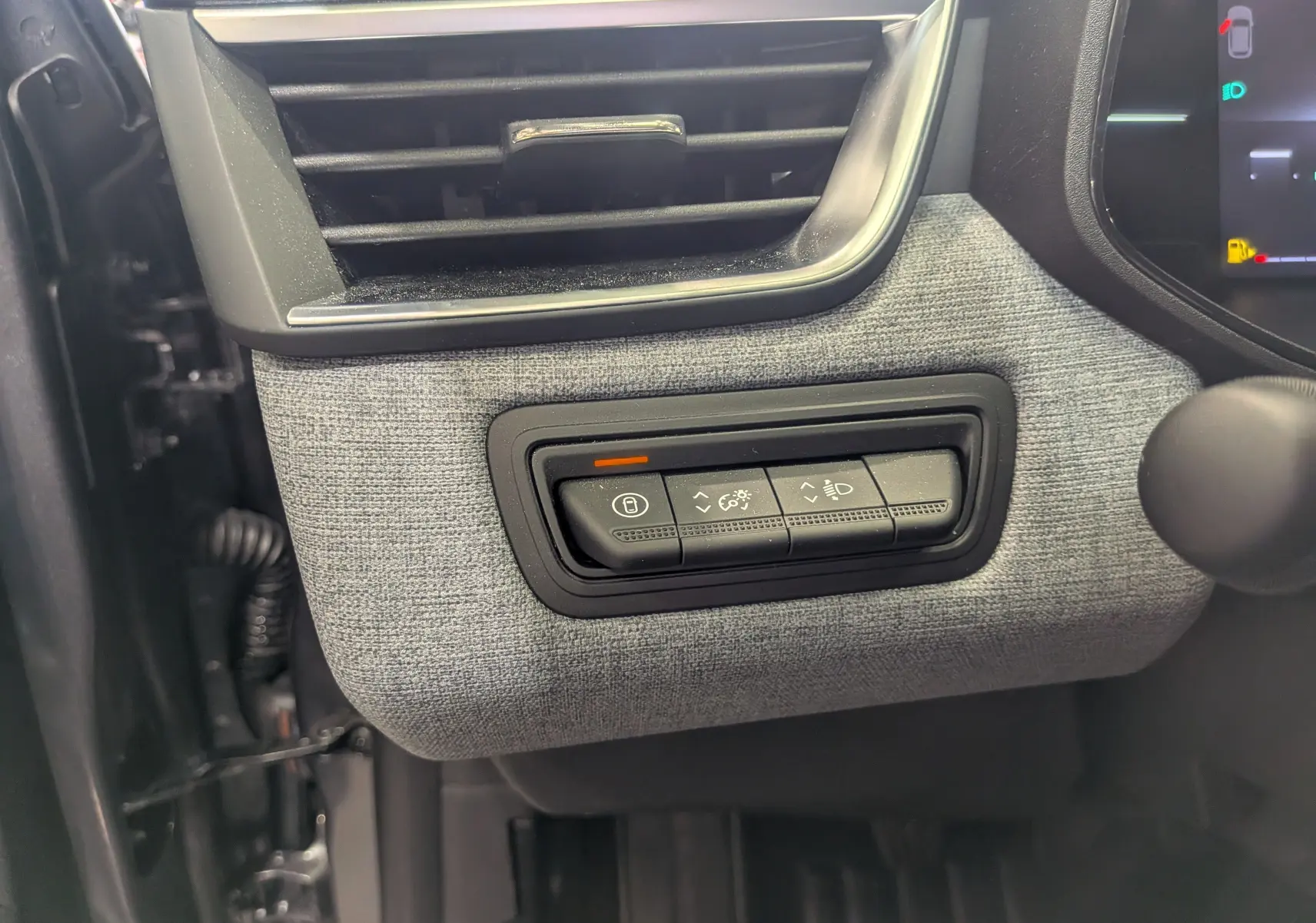 Détail du tableau de bord côté gauche de la Renault Clio V 2025, avec tissu gris schiste et commandes d’éclairage.
