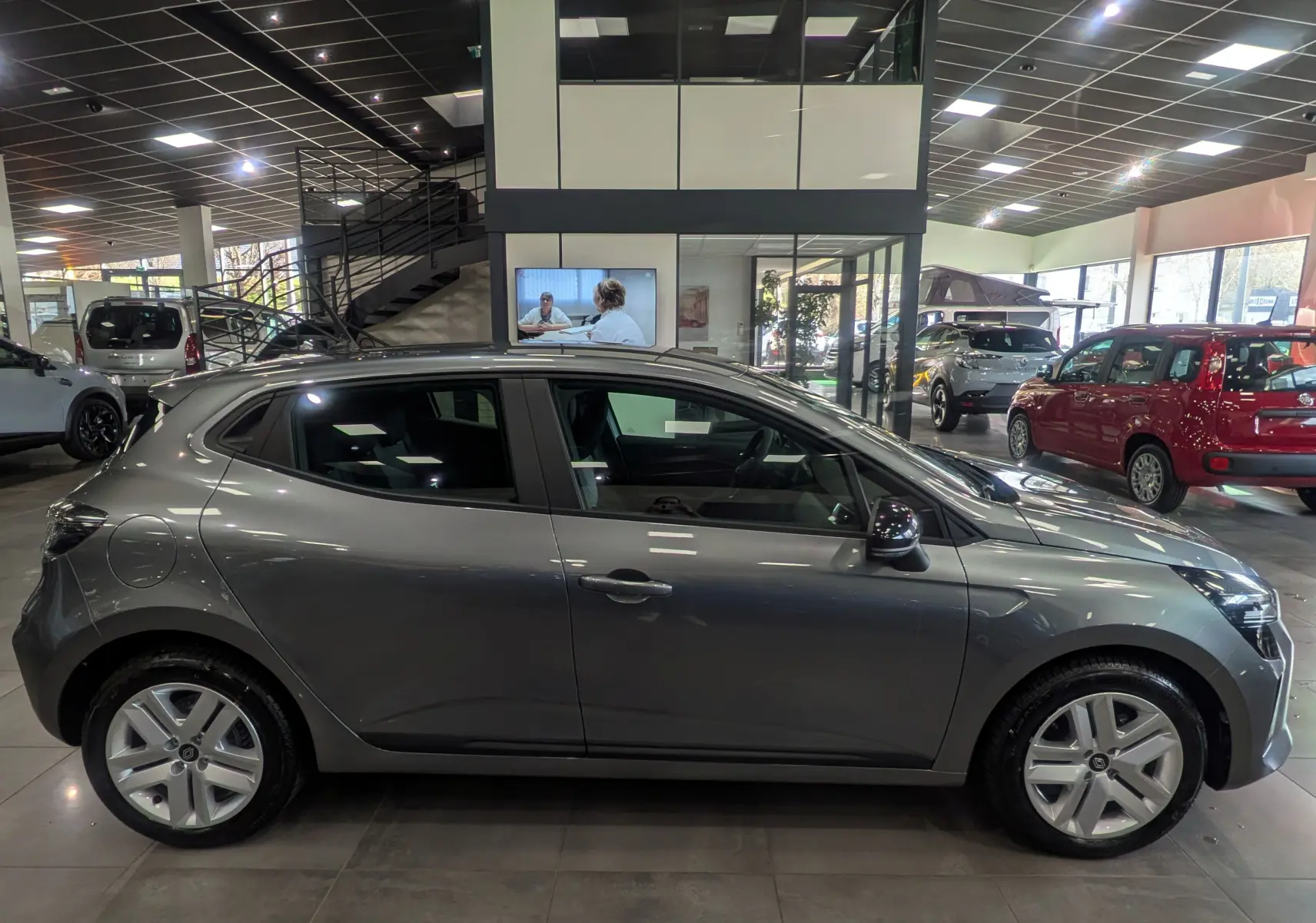 Renault Clio V Blue dCi 100 CH Evolution gris schiste vue de profil côté gauche en intérieur de showroom.