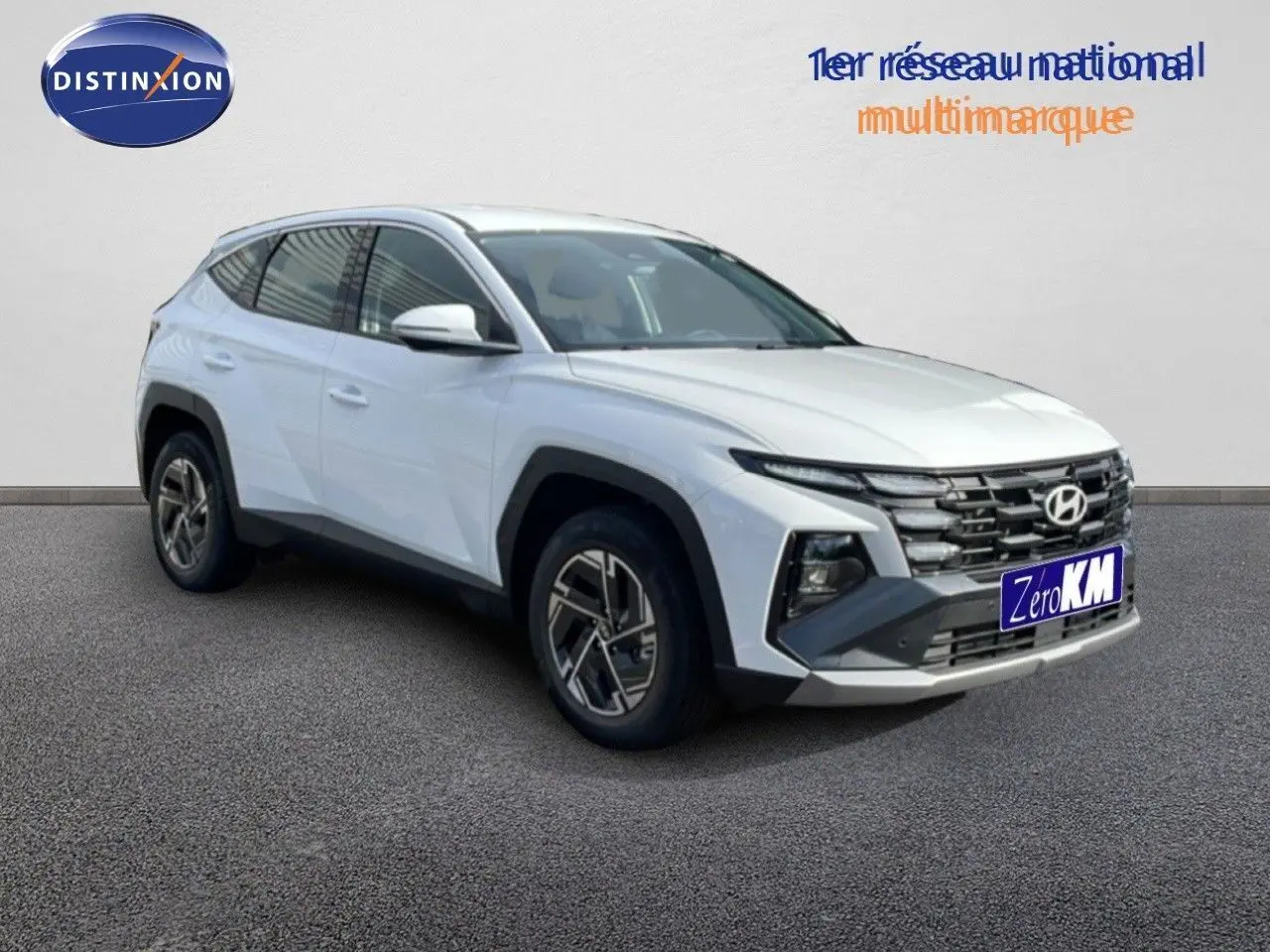 Hyundai Tucson blanc Atlas vu en 3/4 avant droit, avec calandre distinctive et jantes bi-ton modernes.