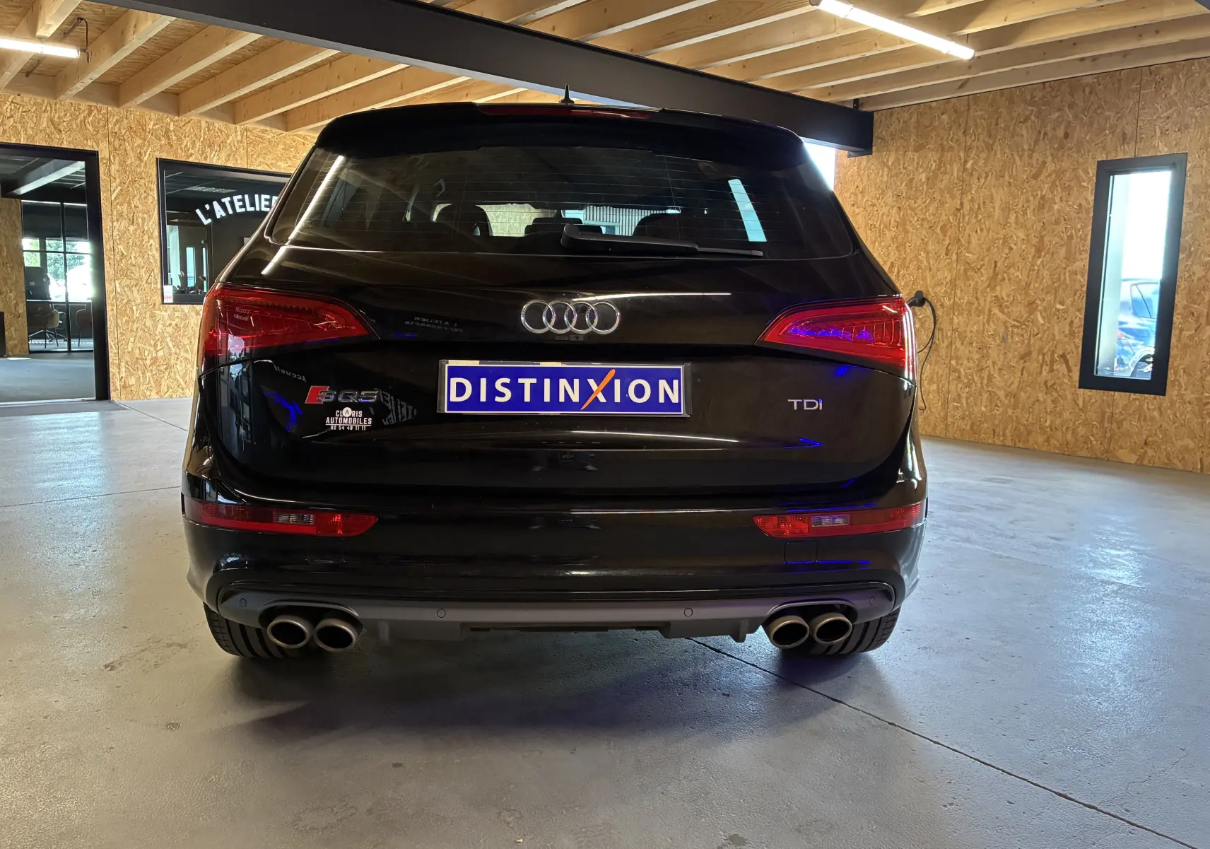 Vue arrière d'un Audi SQ5 noir avec double sortie d'échappement chromée et feux arrière allumés en intérieur.