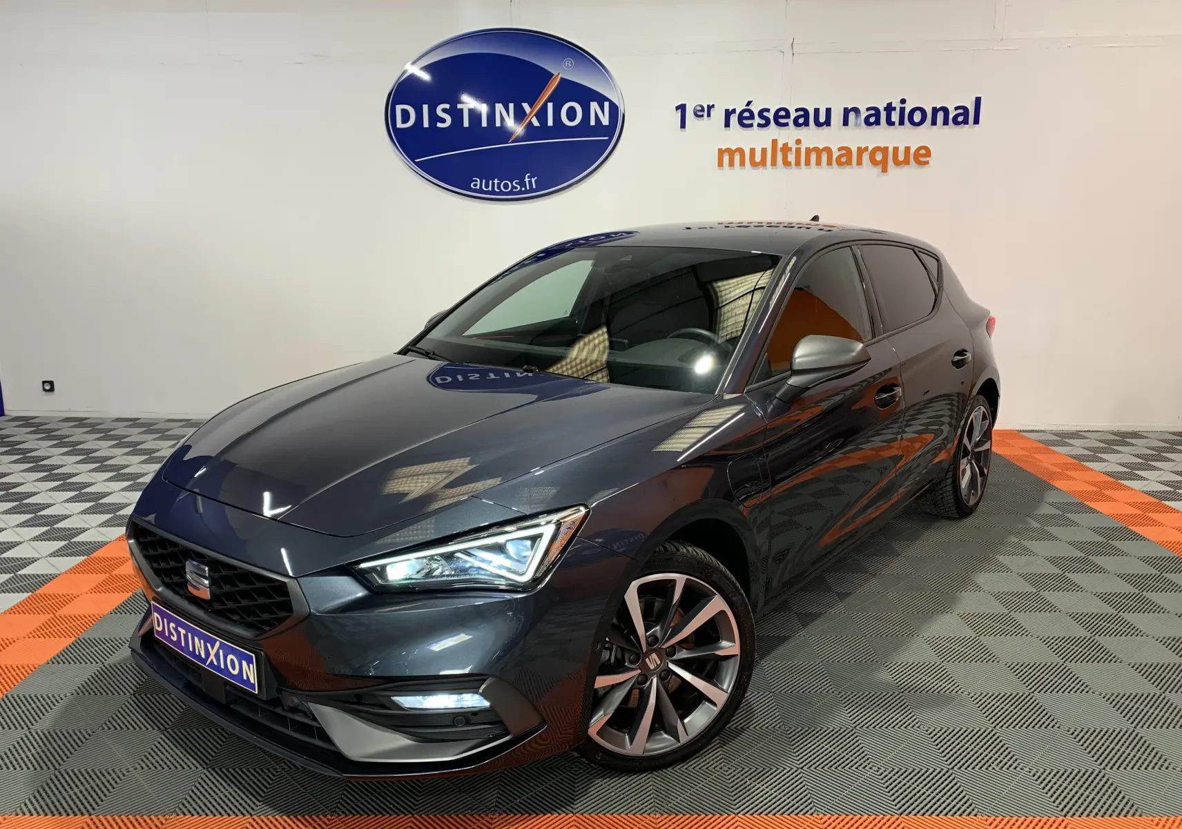 Vue 3/4 avant droite d'une SEAT Leon E-HYBRID 204 FR gris métallisé avec jantes alliage et phares LED allumés