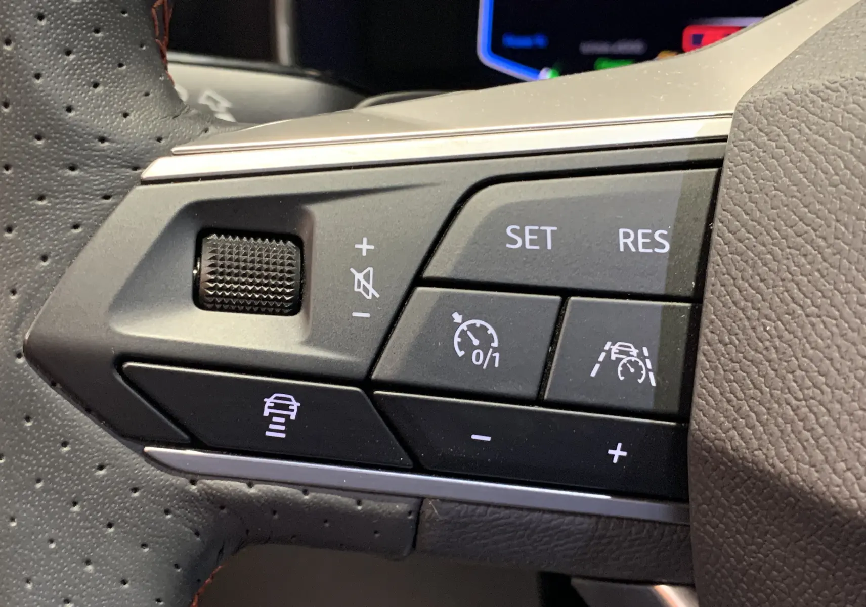 Gros plan sur les commandes de régulateur de vitesse au volant en cuir perforé gris d'une SEAT Leon E-HYBRID 2020.
