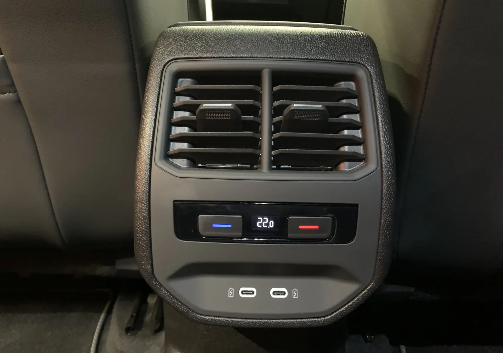 Gros plan sur la console arrière noire du SEAT LEON E-HYBRID 204 FR DSG6 avec ventilation, contrôle de température à 22°C et deux ports USB-C.
