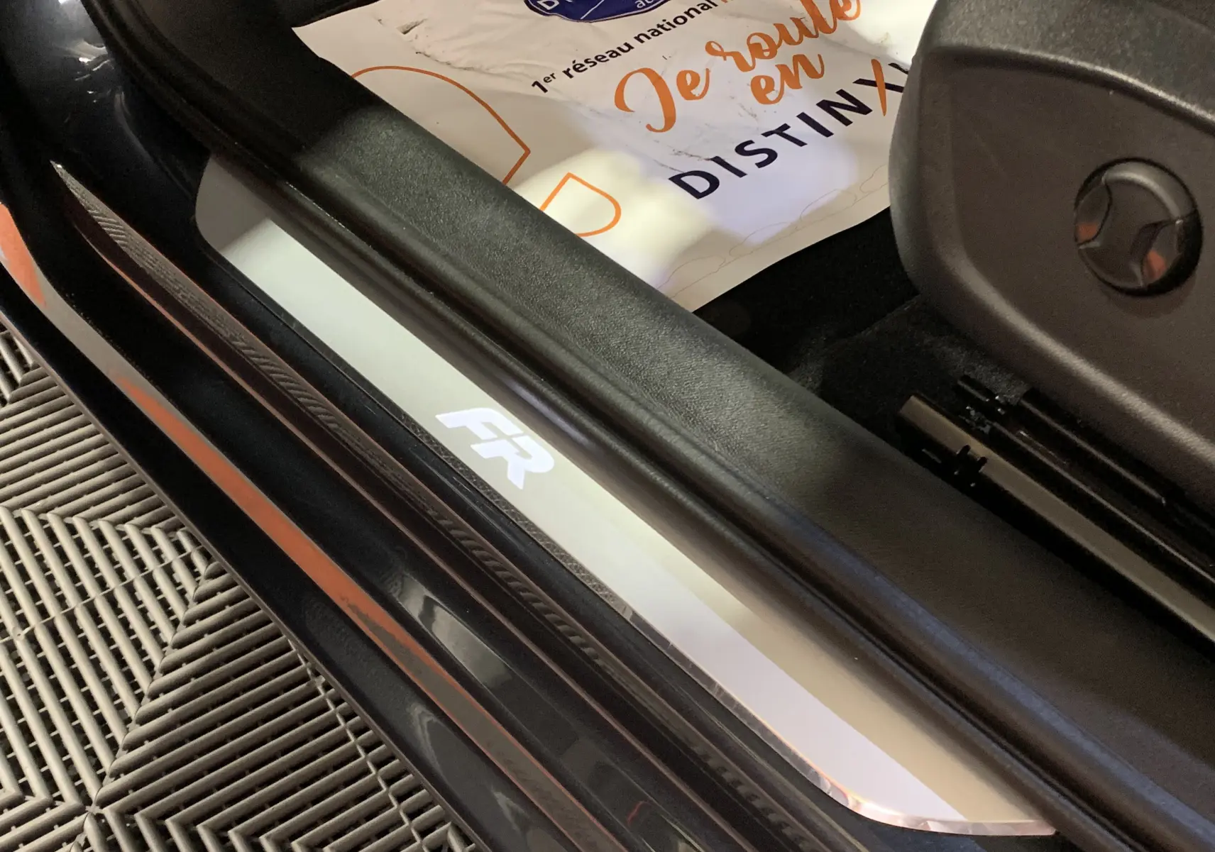 Gros plan sur la plaque de seuil côté gauche avec logo FR d'une SEAT Leon gris, version E-HYBRID 204 FR DSG6.