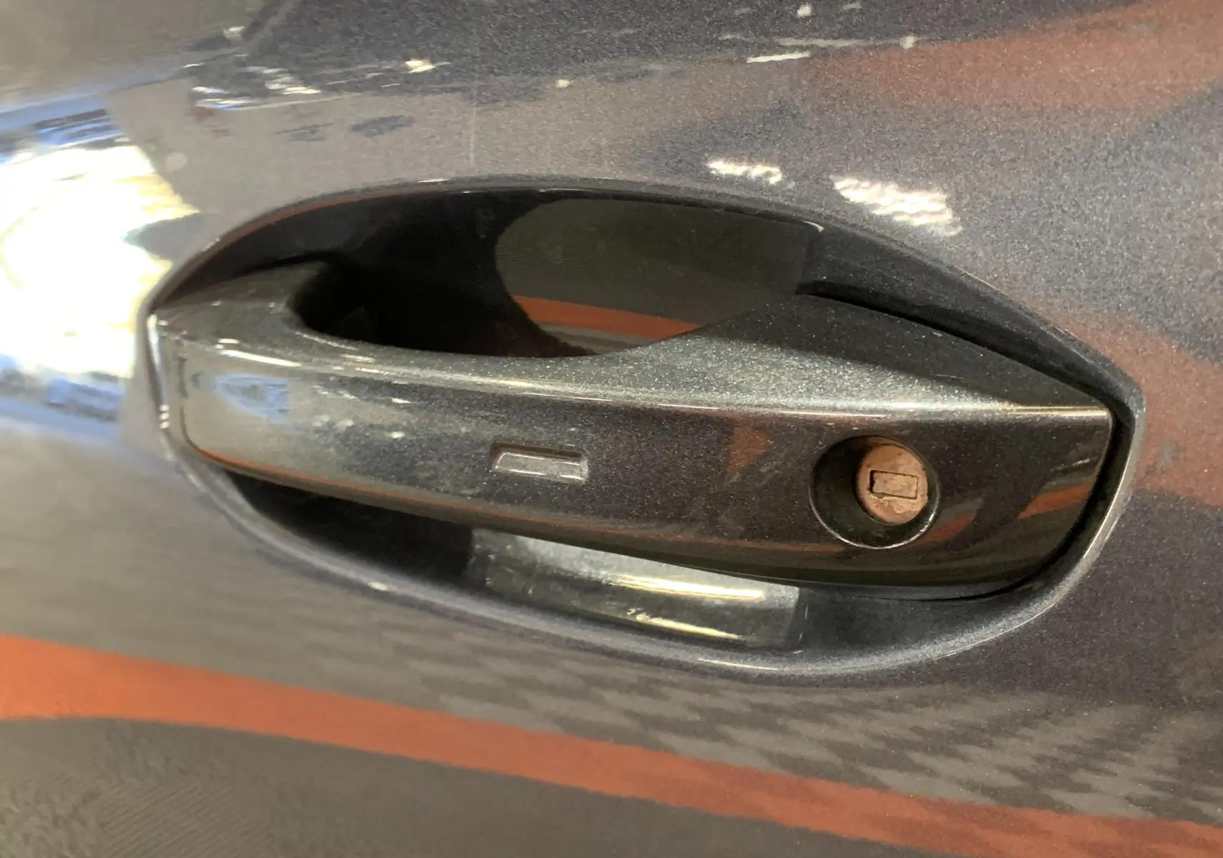 Poignée de porte avant droite gris métallisé d'une SEAT LEON E-HYBRID 204 FR DSG6 de 2020 avec serrure visible.