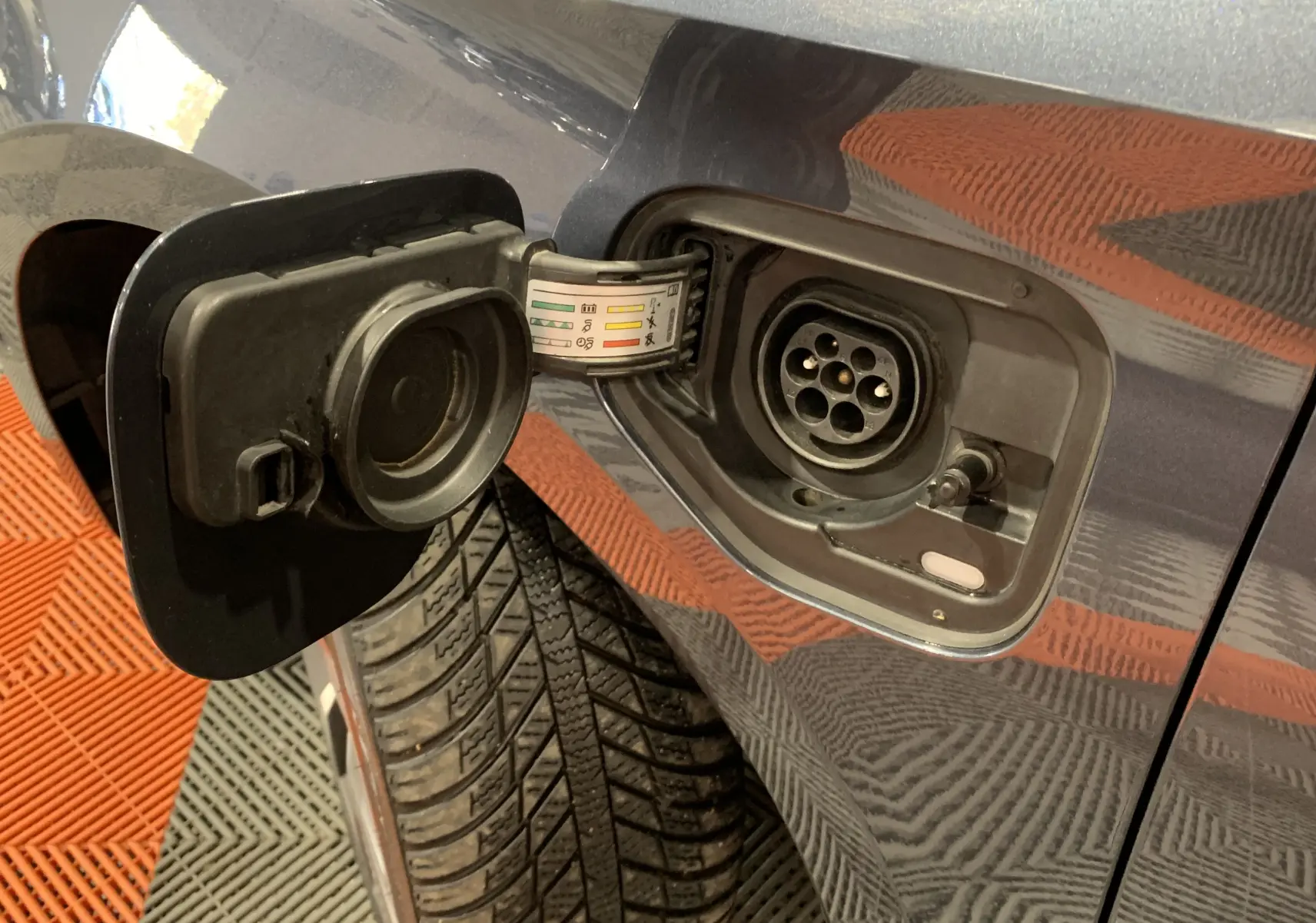 Prise de recharge ouverte côté gauche d'une SEAT LEON E-HYBRID gris 2020, montrant le connecteur électrique.