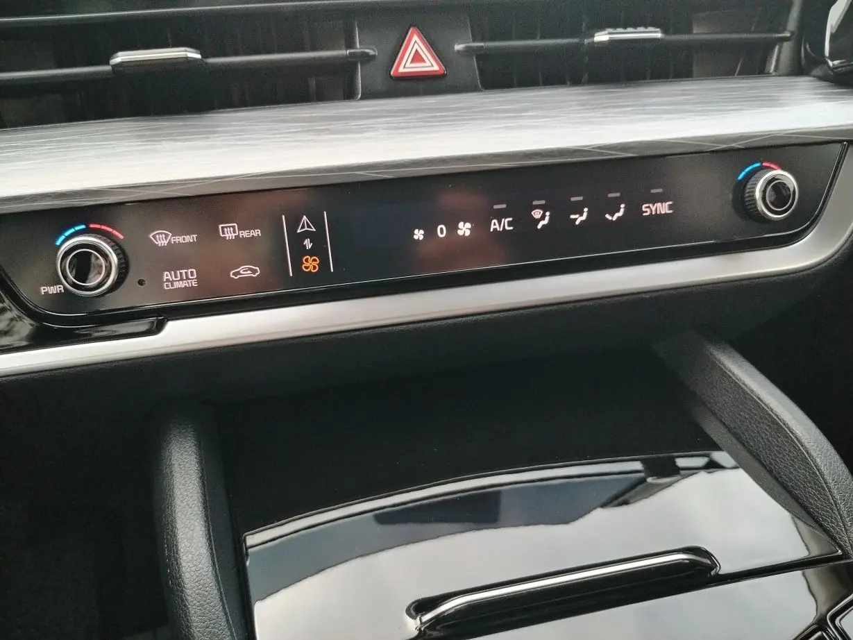 Vue rapprochée de la console centrale du Kia Sportage 2025, avec commandes de climatisation et finition bois gris perle.