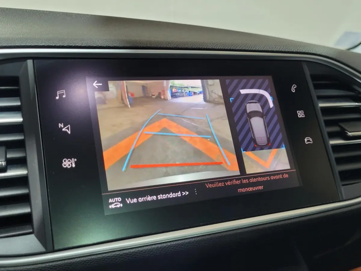 Écran tactile central affichant la caméra de recul et l'aide au stationnement sur Peugeot 308 gris foncé.