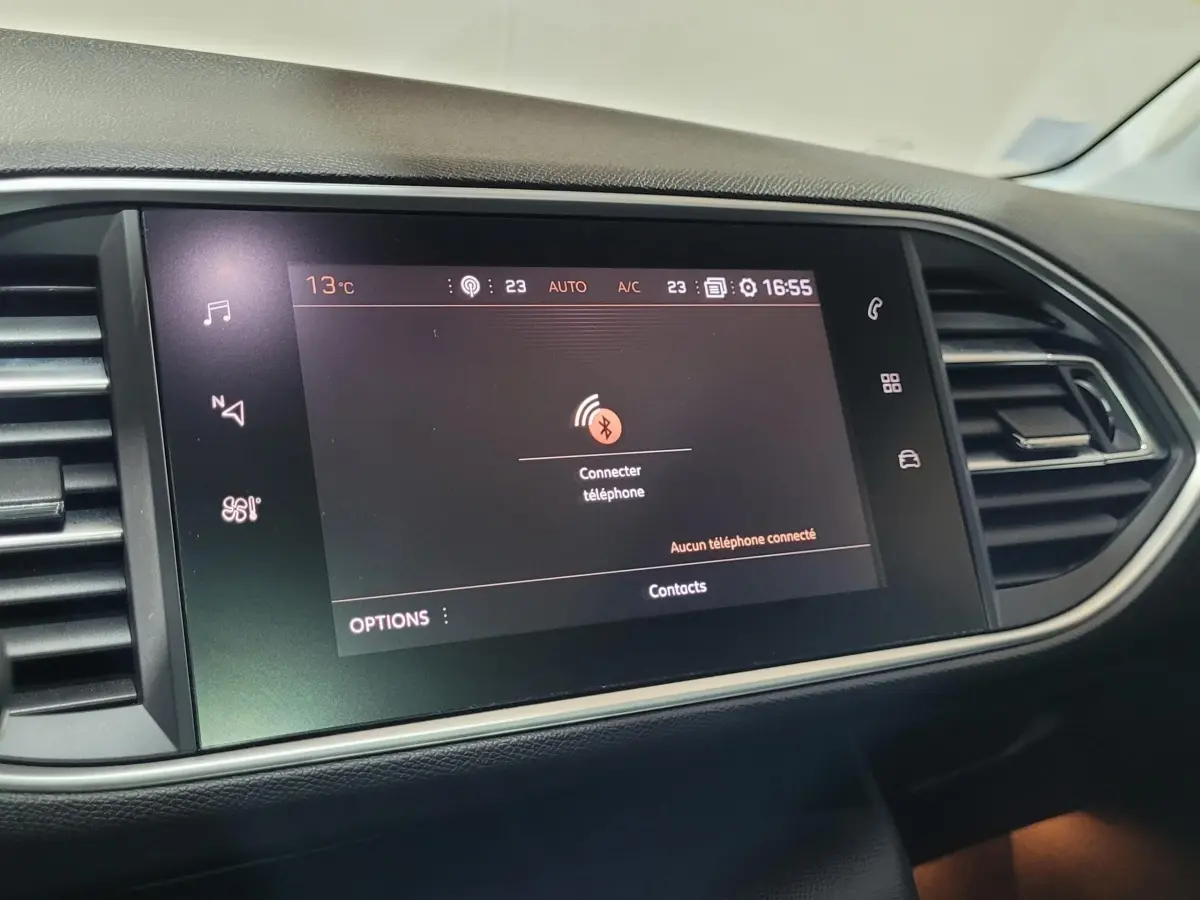 Écran tactile central affichant la connexion Bluetooth dans l'habitacle noir d'une Peugeot 308 gris foncé, vue de face.