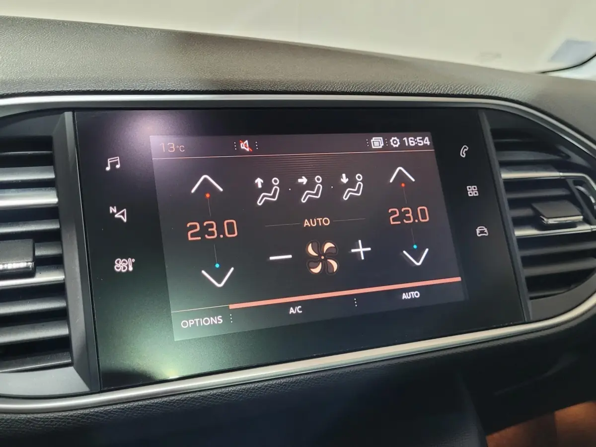 Écran tactile central affichant la climatisation bi-zone à 23°C dans le tableau de bord d'une Peugeot 308 gris foncé.