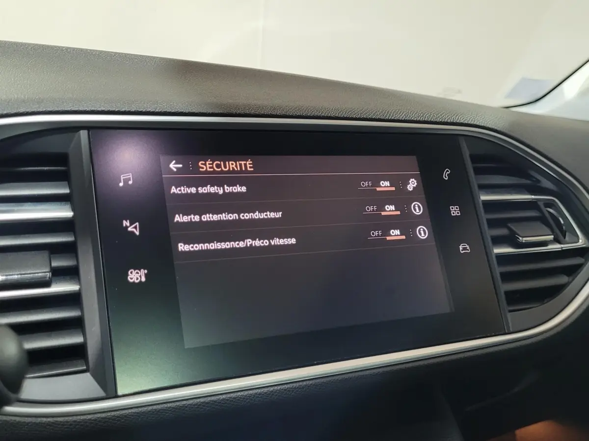 Écran tactile central affichant les réglages de sécurité dans l’habitacle d’une Peugeot 308 gris foncé, vue de face.