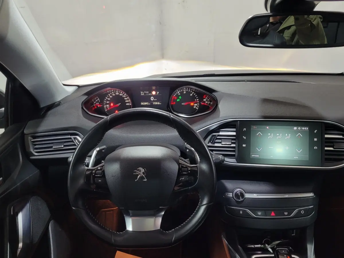 Vue intérieure centrée sur le volant cuir et tableau de bord avec écran tactile de la Peugeot 308 gris foncé de 2020.
