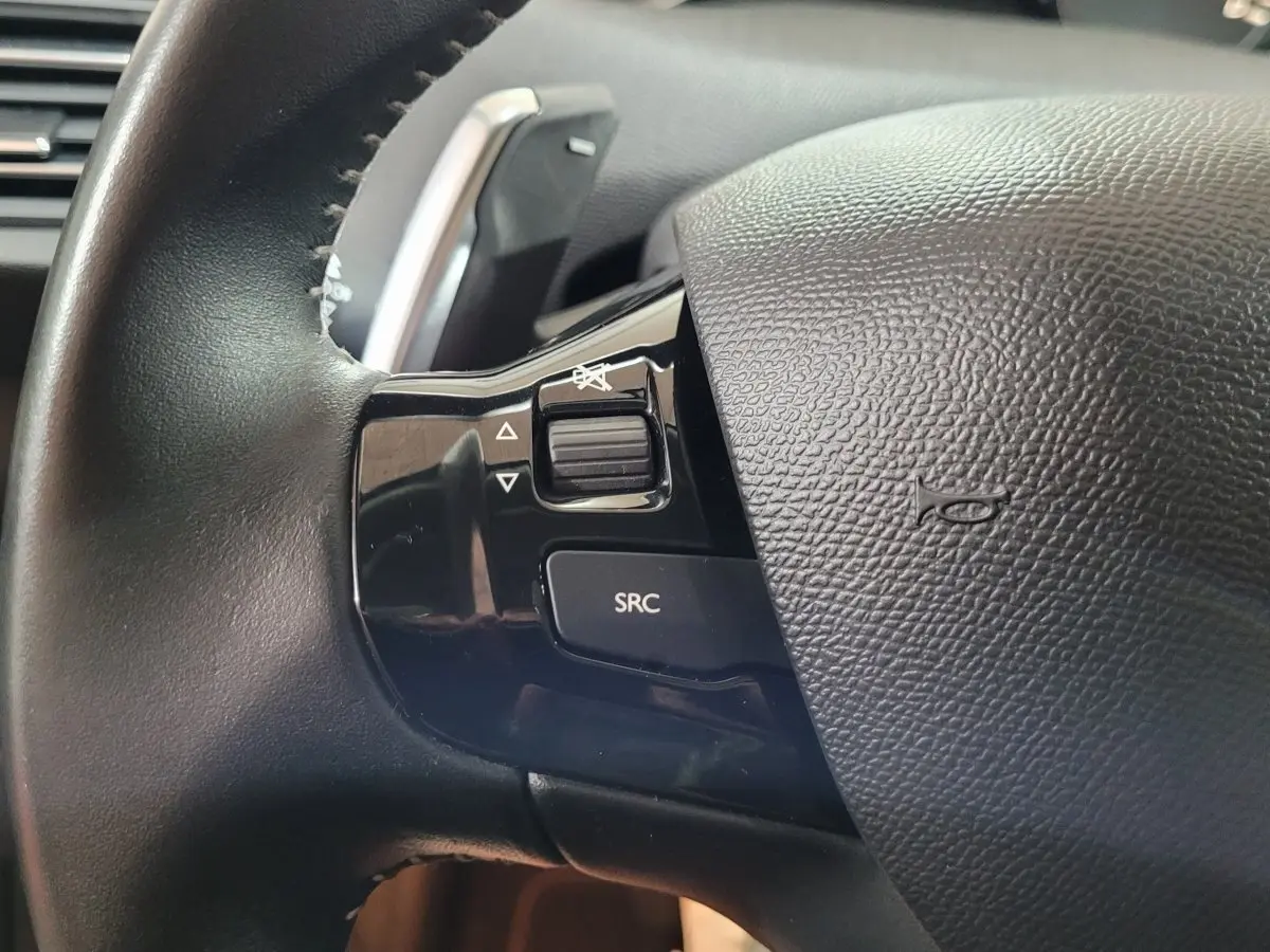 Gros plan sur le côté gauche du volant cuir noir de la Peugeot 308 2020 avec commandes audio intégrées.