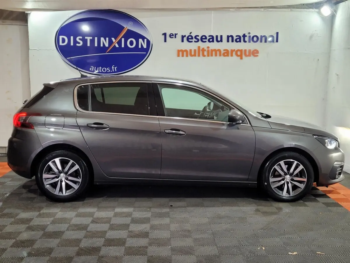 Profil droit d'une Peugeot 308 gris foncé 2020 garée en intérieur avec jantes alliage et vitres teintées.