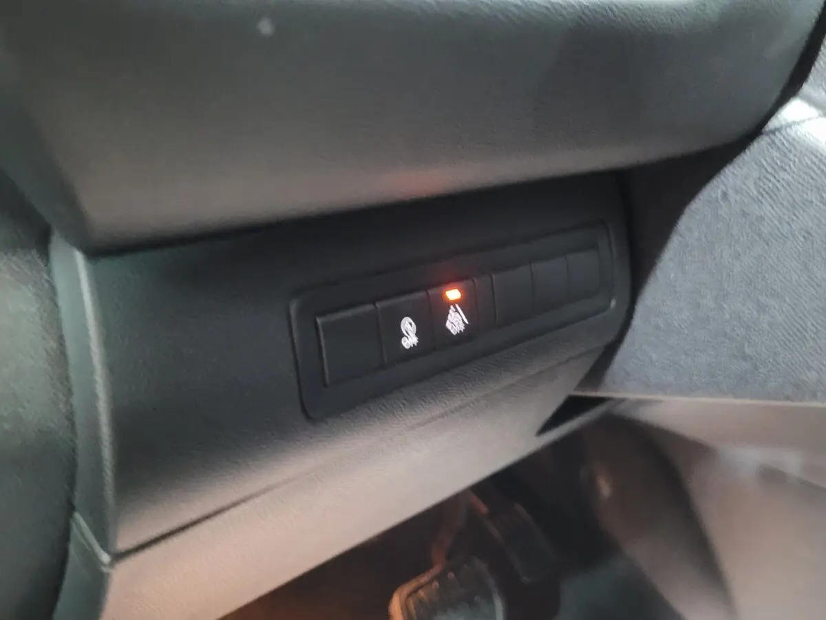 Gros plan sur les commandes de sécurité avec témoin lumineux activé, côté gauche intérieur d'une Peugeot 308 gris foncé 2020.