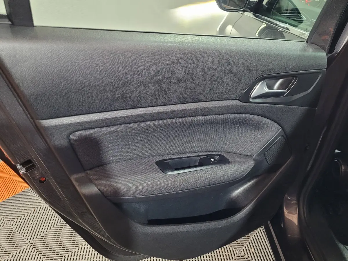 Porte intérieure côté gauche en tissu noir de la Peugeot 308 BlueHDi 130 gris foncé, avec poignée et commande vitre.