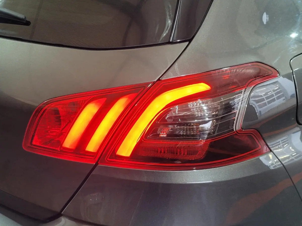 Gros plan sur le feu arrière droit allumé d'une Peugeot 308 gris foncé, version BlueHDi 130 de 2020.
