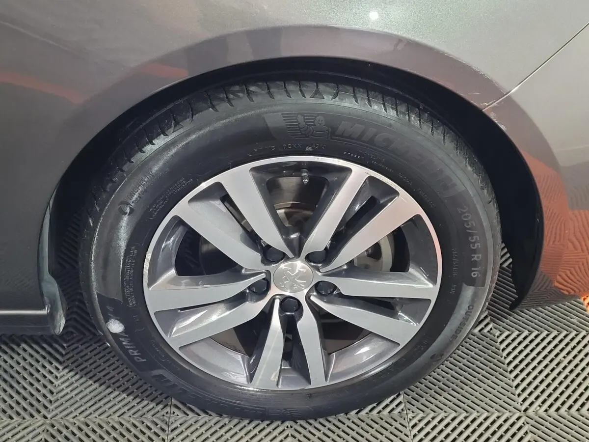 Gros plan sur la roue avant gauche d'une Peugeot 308 gris foncé avec jante alliage et pneu Michelin.