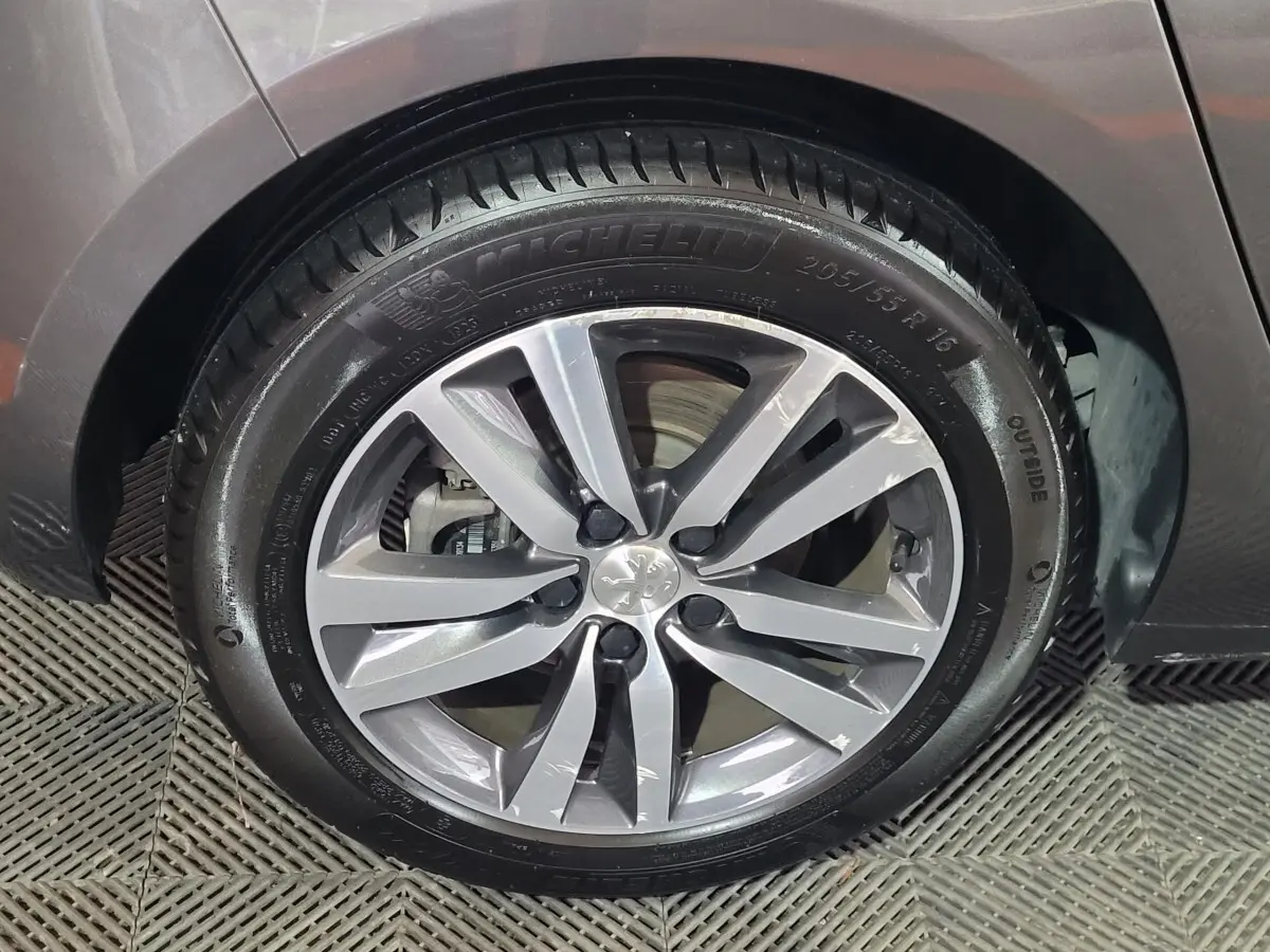 Gros plan sur la roue avant gauche de la Peugeot 308 gris foncé, avec jante alliage et pneu Michelin.