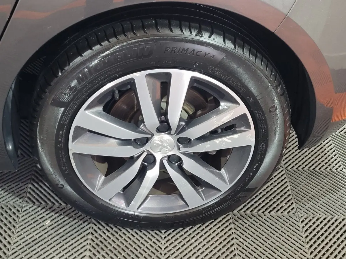 Gros plan sur la jante alliage gris et pneu Michelin d'une Peugeot 308 gris foncé, côté arrière droit.
