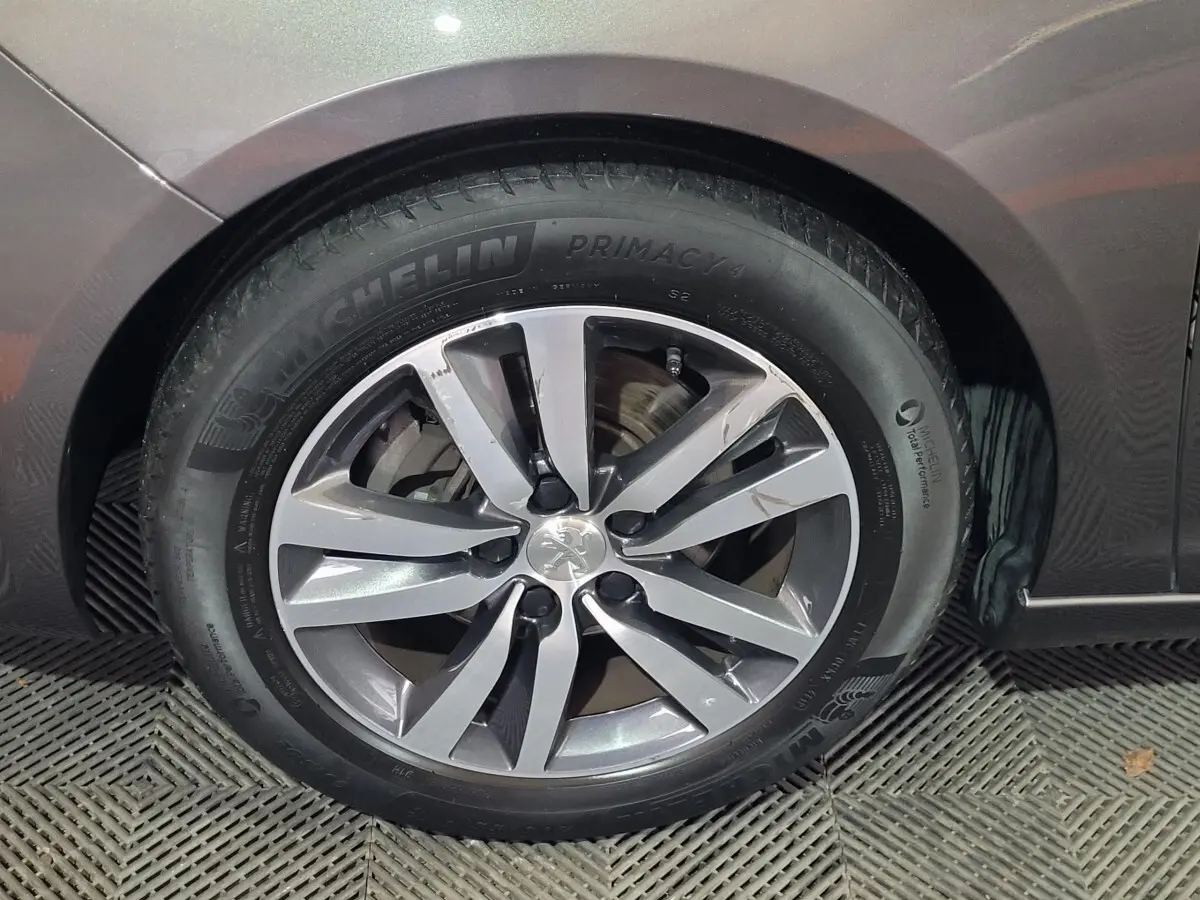 Gros plan sur la roue avant gauche d'une Peugeot 308 gris foncé, avec jante alliage et pneu Michelin Primacy 4.